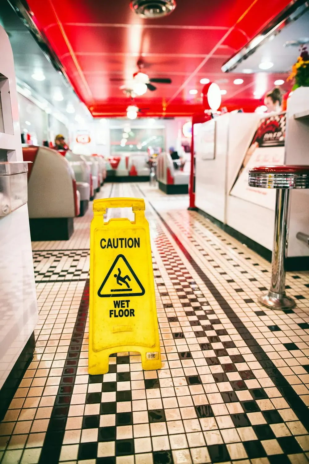 Yellow wet-floor sign on a freshly mopped tile floor in a diner