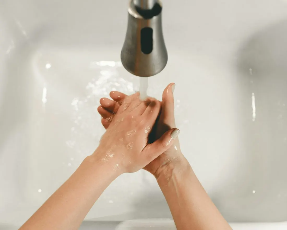 Hands being washed under a running faucet