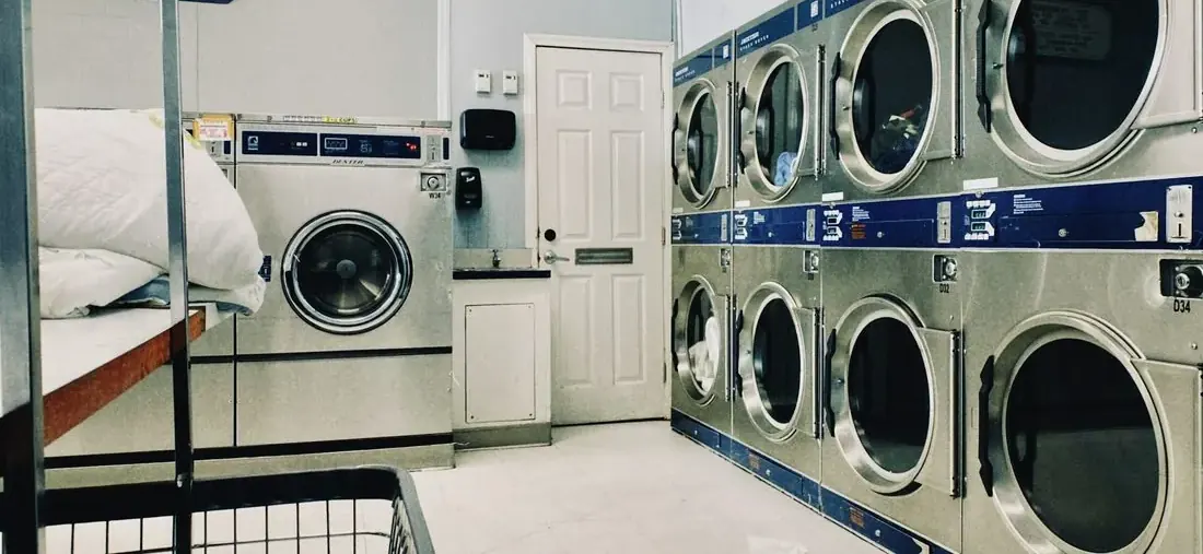 Stacked commercial dryers and a front-load washer in a laundry room