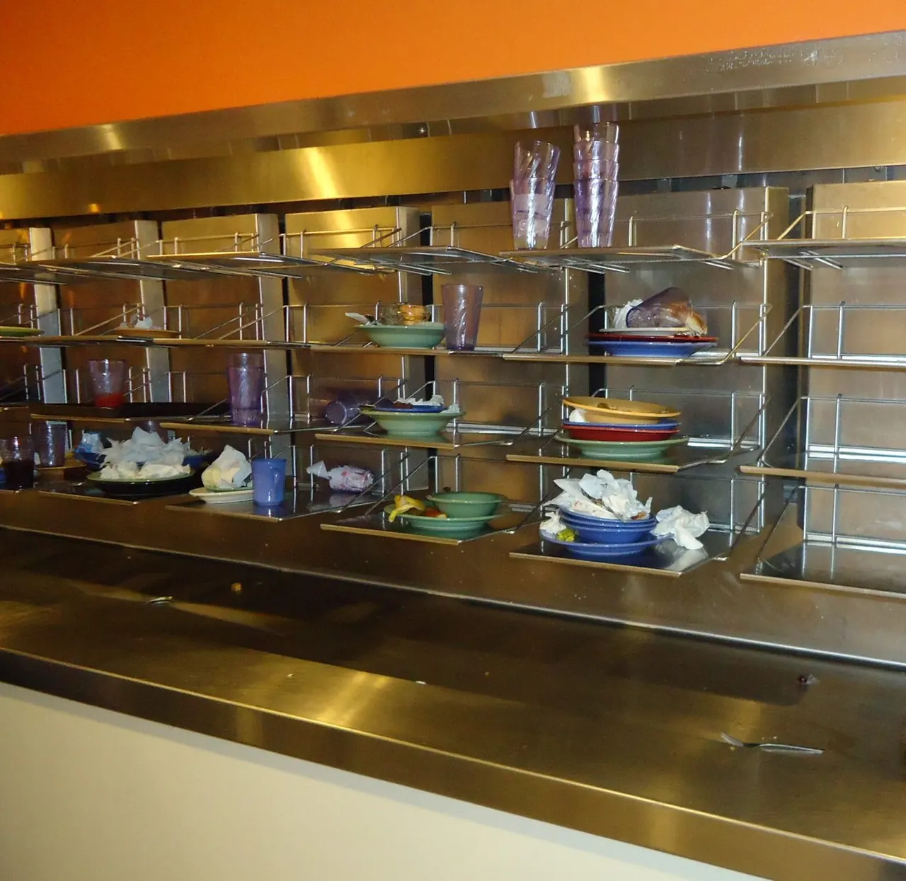 Stainless steel dish return rack with used plates, bowls and cups